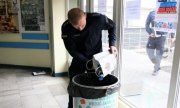 policjant wysypuje zebrane plastikowe nakrętki do specjalnego pojemnika