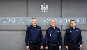Dwaj policjanci z Buska Zdroju w mundurach z Komendantem Głównym Policji, w tle napis: Komenda Główna Policji