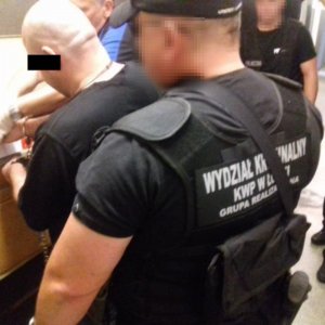 widać podejrzanego podczas daktyloskopii a za nim policjant wydziału kryminalnego KWP w Łodzi