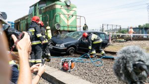 strażacy podczas akcji ratunkowej przy samochodzie, w który uderzył pociąg