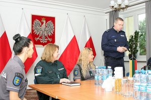 litewscy oraz polscy policjanci siedzą przy stole w trakcie spotkania w Komendzie Głównej Policji, jeden z polskich policjantów stoi i przemawia