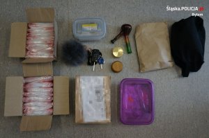 zabezpieczone przez policjantów narkotyki w woreczkach, kluczyki do samochodu, dwa pudełka plastikowe i fajka do palenia narkotyków