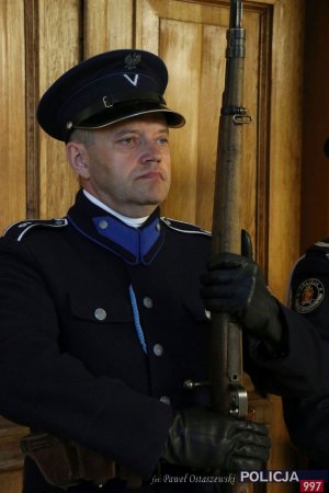 Policjant, a jednocześnie rekonstruktor na warcie przed tablicą patrona KGP