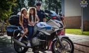 Dziewczynki na motocyklu policyjnym z tyłu policjant