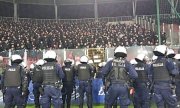 Policjanci stoją na płycie stadionu przed sektorem gości