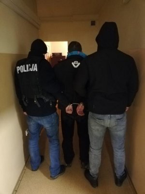 mężczyzna zatrzymany stojący po między dwoma policjantami