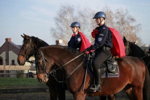 dwoje policjantów na koniach z workami z prezentami