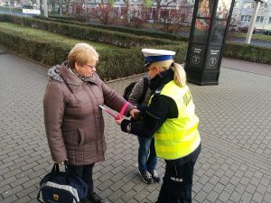 policjantka ruchu drogowego rozdaje odblaski seniorom z okazji dnia babci i dziadka