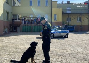 Policjant z psem podczas pokazu, z tyłu grupa dzieci