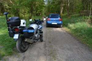 auto, którym uciekał kierujący i policyjny motocykl na leśnej drodze