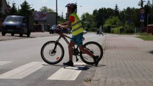 dziecko przeprowadza rower przez przejście dla pieszych