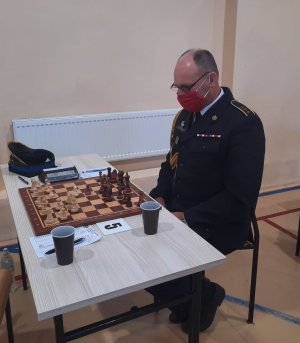 Przedstawiciel Straży Pożarnej siedzi przy stoliku z szachami