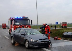 uszkodzony pojazd, wozy strażackie i strażacy na miejscu wypadku