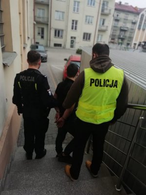 dwaj policjanci prowadzą zatrzymanego mężczyznę