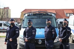 Czterej policjanci z Oddziału Prewencji Policji w Poznaniu, którzy uratowali 16-miesięczną dziewczynkę, na tle oznakowanego radiowozu.&quot;&gt;