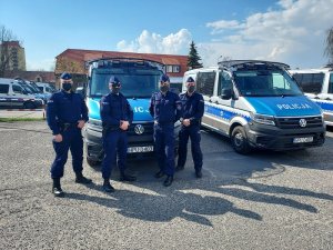 Czterej policjanci z Oddziału Prewencji Policji w Poznaniu, którzy uratowali 16-miesięczną dziewczynkę, na tle oznakowanego radiowozu.&quot;&gt;