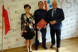 Starosta nyski Andrzej Kruczkiewicz oraz dyrektor PCPR w Nysie Krystyna Wilisowska z nagrodzonym policjantem