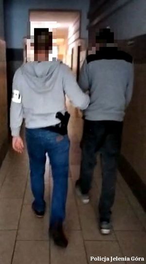 nieumundurowany policjant prowadzi mężczyznę poszukiwanego korytarzem