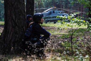 policjanci w lesie w trakcie ćwiczeń, w tle policyjny śmigłowiec