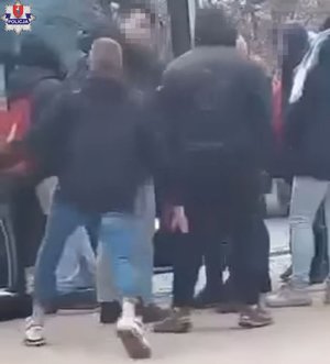grupa osób wsiadających do autobusu, wśród nich jest agresywny młody mężczyzna, który usiłuje uderzyć drugą osobę