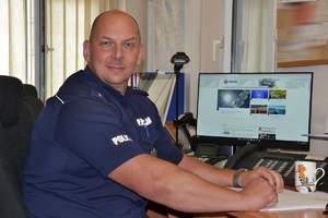 policjant siedzi przy biurku, na którym stoi ekran komputera