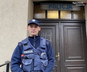 sierżant Roch przed drzwiami, nad którymi widnieje napis policja
