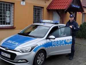 policjant stoi przy radiowozie zaparkowanym przy budynku Posterunku Policji w Przechlewie