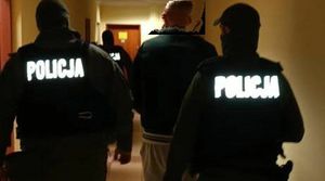 Policjanci prowadzą zatrzymanego przez korytarz
