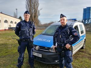 dwaj policjanci ogniwa patrolowo-interwencyjnego stoją przy radiowozie