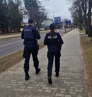Policjant i policjantka idą ulicą podczas patrolu.