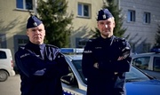 Dwaj policjanci st. sierż. Grzegorz Zieliński, st. post. Andrzej Ciechanowski stoją przy radiowozie policyjnym