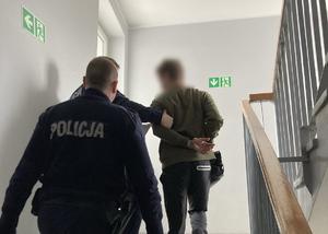 Policjanci prowadzą po schodach zatrzymanego