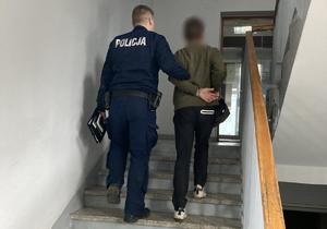 Policjant prowadzi po schodach zatrzymanego