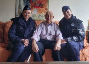 dwie umundurowane policjantki siedzą na kanapie ze starszym panem