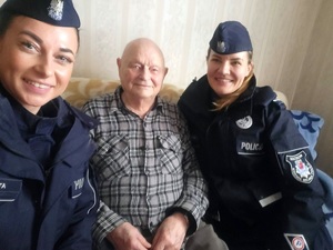 dwie umundurowane policjantki siedzą na kanapie ze starszym panem