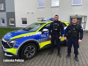 Dwóch policjantów stoi przy radiowozie