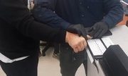 policjant pobiera odciski palców zatrzymanemu