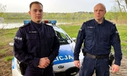 dwóch umundurowanych policjantów stoi na tle radiowozu