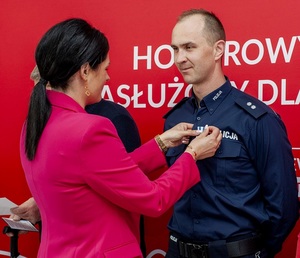 kobieta przypina odznakę policjantowi
