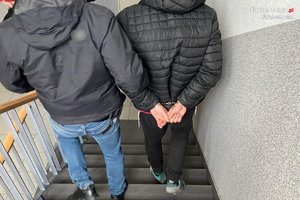 policjant z zatrzymanym idą po schodach w dół