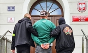 dwaj policjanci prowadzą po schodach do budynku Komendy Powiatowej Policji w Brzegu zatrzymanego mężczyznę zakutego w kajdanki