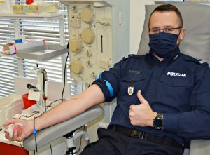 Policjant oddający krew z uniesionym kciukiem
