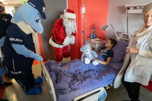 Polfin i Mikołaj rozmawiają z małym pacjentem, który leży w łóżku z misiem