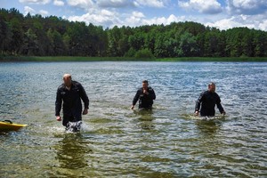 trzech policjantów wychodzi z wody w pełnym umundurowaniu