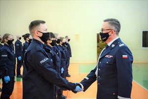 Sala gimnastyczna Oddziału Prewencji Policji w Łodzi, uroczystość ślubowania, komendant wojewódzki gratuluje nowo przyjętym policjantom.
