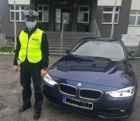 przed budynkiem KPP Sieradz stoi nieoznakowany radiowóz BMW obok niego umundurowany policjant w kamizelce odblaskowej , na twarzy ma założona maseczkę