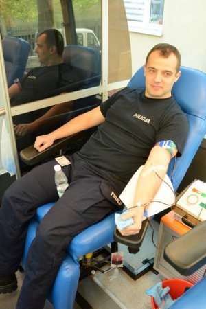 Policjant w mundurze, siedzący na fotelu, oddający krew