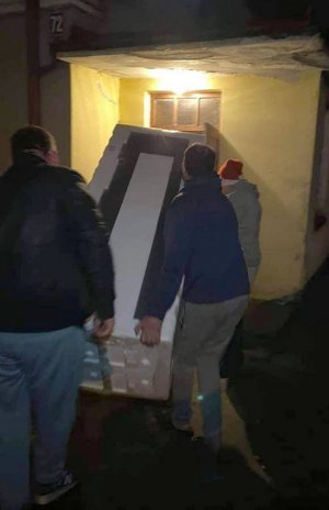Mężczyźni wnoszący lodówkę do mieszkania