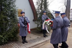 Na zdjęciu mężczyźni w policyjnych mundurach składają wiązankę kwiatów i znicz pod tablicą pamiątkową poświęconą podkom. Tadeuszowi Bartosikowi.