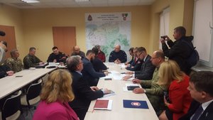 Posiedzenie sztabu kryzysowego w Bielsku - Białej. Przedstawiciele służb i instytucji siedzą przy stole prowadząc rozmowy.